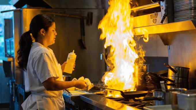 Female chef cooking with a flaming pan