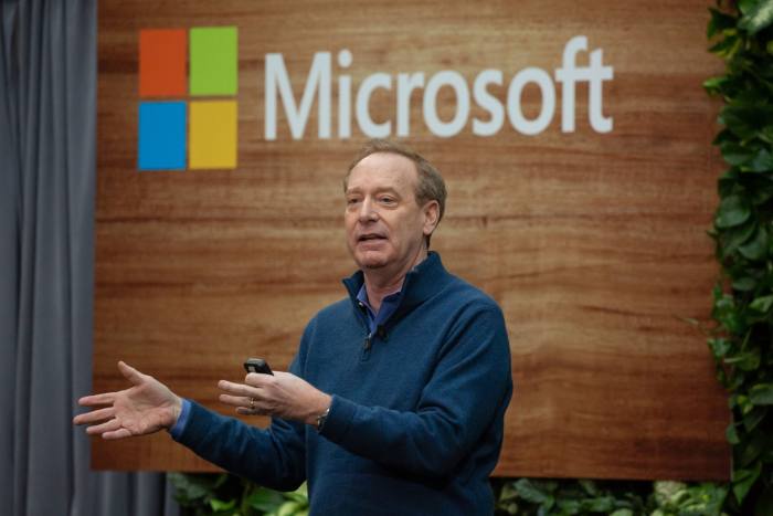 Brad Smith in front of a Microsoft logo