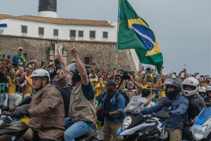 Bolsonaro, left, rides a motorbike past supporters in the city of Salvador during the summer. More recently he has attended mobile campaign events, with thousands joining him on two wheels