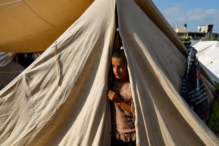 Una ragazza palestinese guarda fuori da una tenda