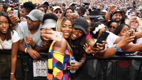 A female singer poses for selfies with fans at the front row of a concert
