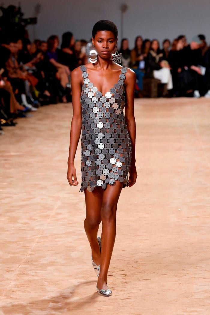 A catwalk model wears a short dress that resembles a suit of chain mail