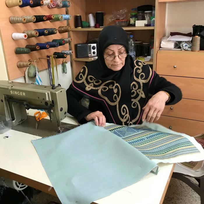 A female artisan weaves together a piece of cloth