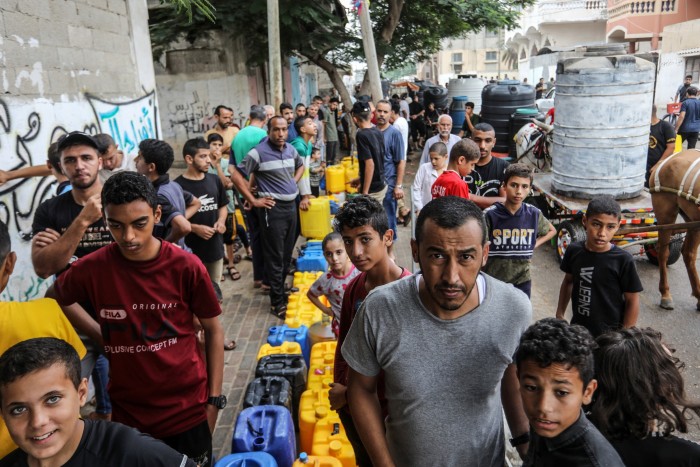 Palästinenser warten an einer Wasserstelle, um Behälter aufzufüllen
