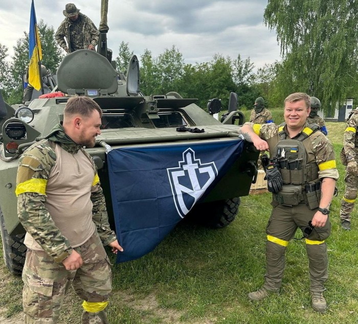 Aleksandr Skachkov, rechts, mit anderen Mitgliedern des russischen Freiwilligenkorps neben einem gepanzerten Fahrzeug