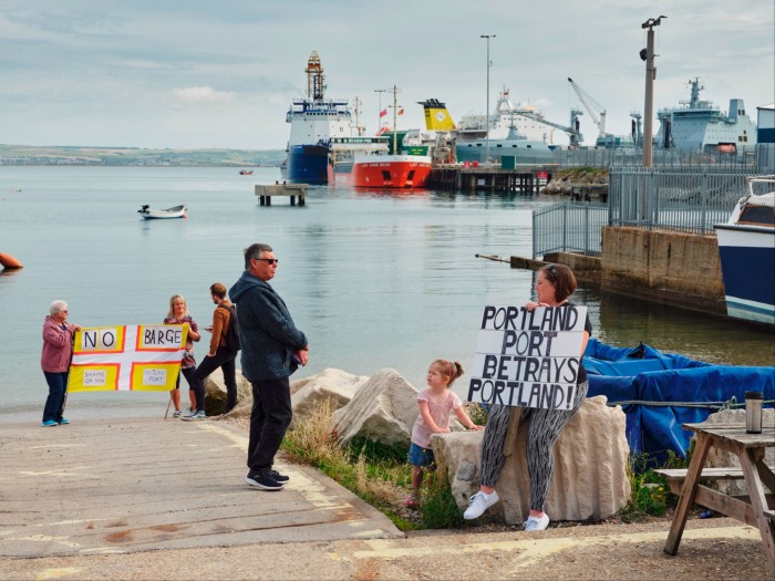 Some people hold signs saying ‘No Barge’ and ‘Portland Port Betrays Portland’ 