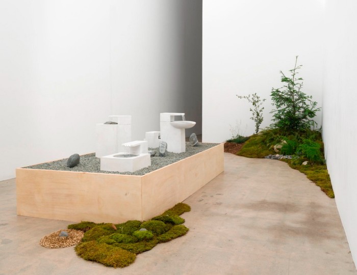 White boxy sanitaryware items on a plinth surrounded by an ornamental garden