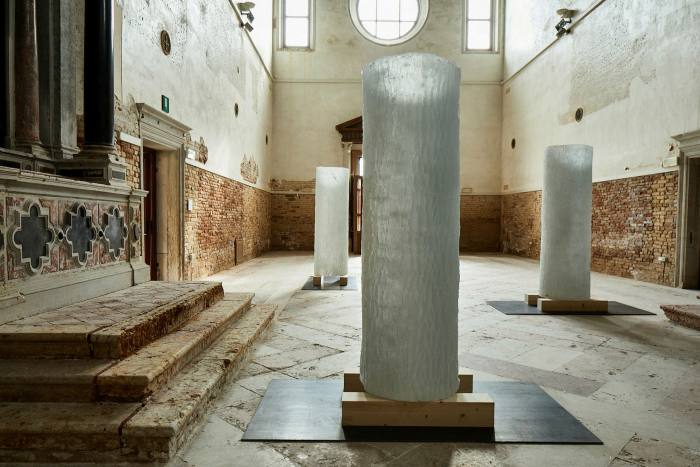 The interior of a church is dotted with white textured glass tubes sitting on short wooden planks