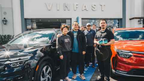 People standing in front of VinFast vehicles at a VinFast dealership