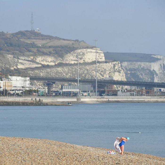 A swimmer on the shore at Dover Harbour –behind her are the port and the white cliffs
