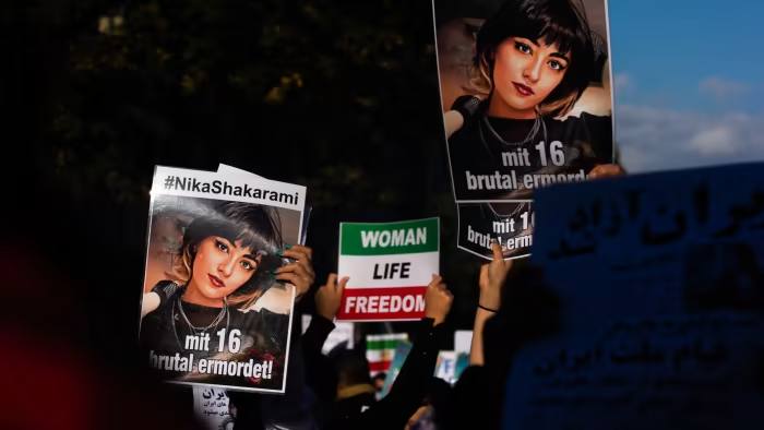 Pictures of Iranian teenager Nika Shakarami, who died last month in mysterious circumstances, are held aloft at a protest in Düsseldorf, Germany