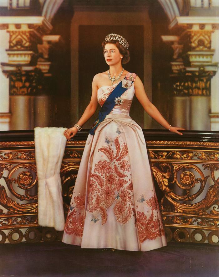 A formal portrait released in 1959 shows the young Queen posing in formal dress, wearing a crown and long white gown with red embroidery 
