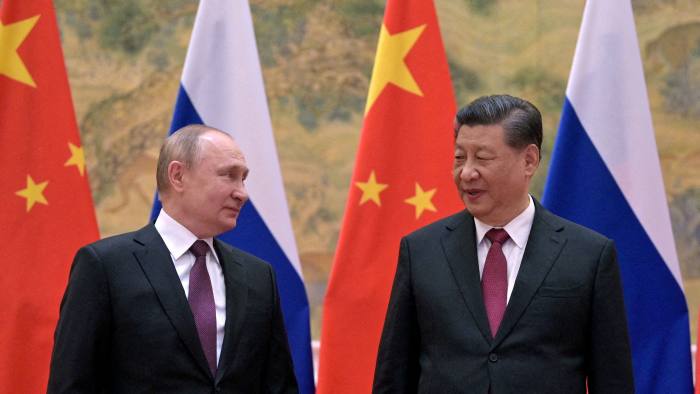 Vladimir Putin and Xi Jinping in front of their flags