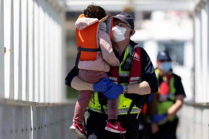 A UK Border Force official holds a young girl who arrived with other migrants after being picked up in a dinghy in the English Channel this summer