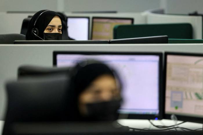 Saudi women with masks work in a call center in Mecca