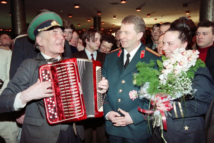 Vladimir Zhirinovsky and his wife Galina Lebedeva listen to a retired officer playing an accordion during a party marking Defenders Day