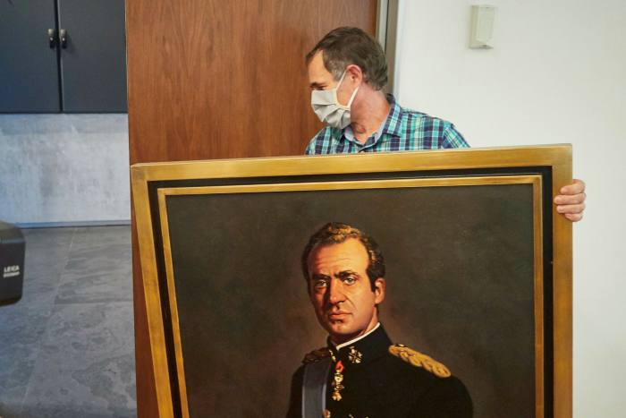A man wearing a mask carries a portrait of Spain’s former king Juan Carlos that is being removed from a legislative chamber in Navarre