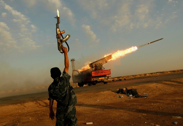 A Libyan rebel celebrates as his comrades fire a rocket at Gaddafi’s troops in 2011. Stories of brutality and abuse are common among the thousands of people who have passed through the country since the dictator was overthrown