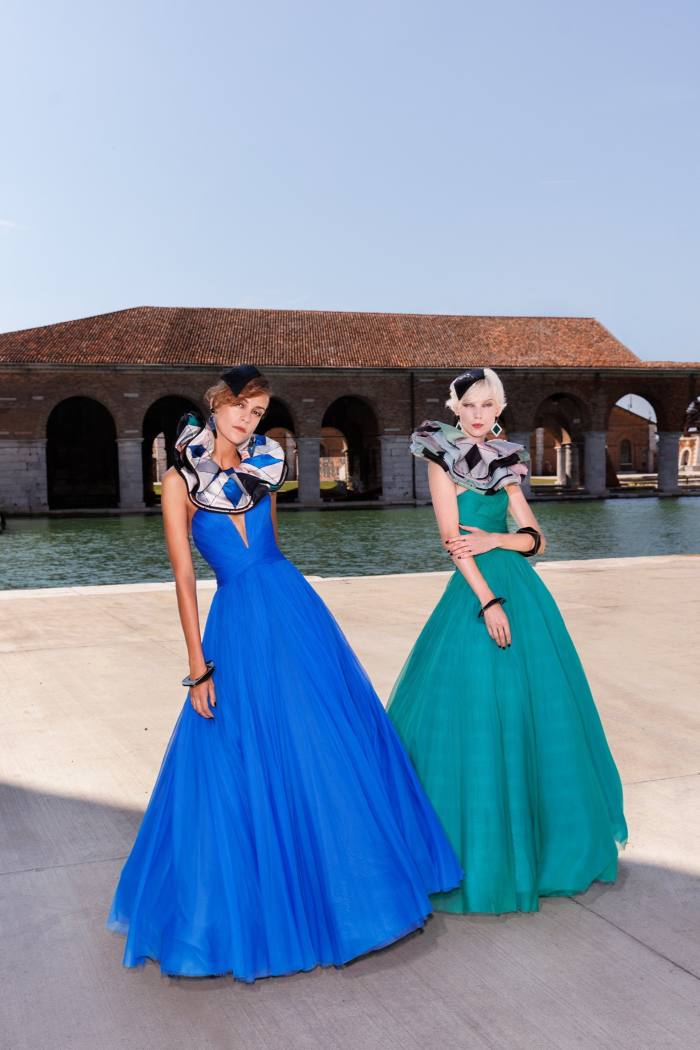 Two models pose in blue and turquoise full-length dresses 
