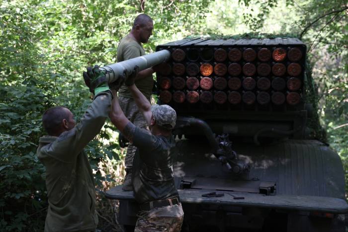 Ukrainian artillerymen load missiles onto a self-propelled multiple rocket launcher