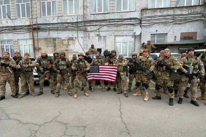 Ukrainian soldiers in khaki combat gear display an American flag