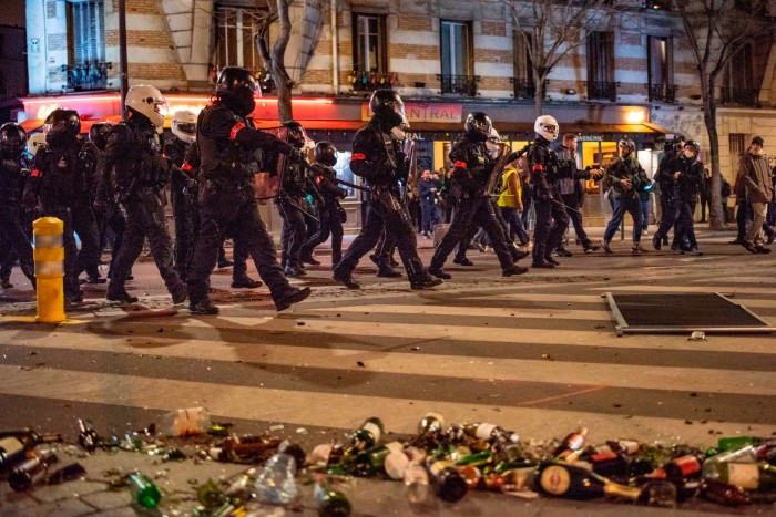 French riot police with shields and batons advancing towards the crowd 