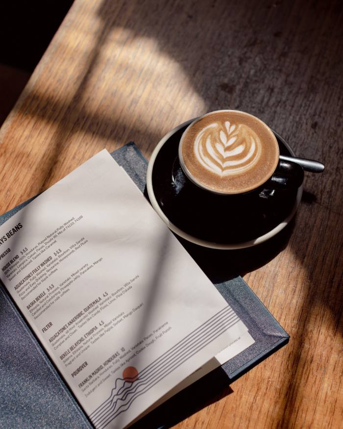 A cup of ‘magic’ coffee beside a menu in Seven Seeds