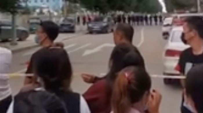 An image from a video taken last month shows parents gathering behind a police line outside a school in Tongliao, Inner Mongolia