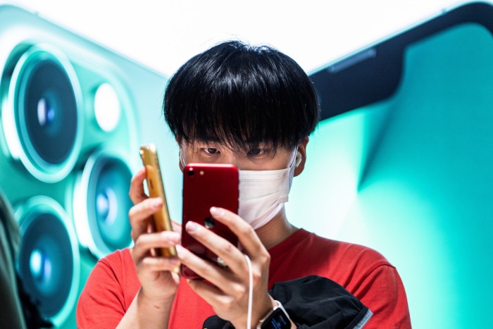 A Chinese customer wearing a mask tries an iPhone 
