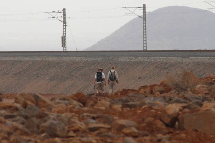 Two men walk the track through rocky land