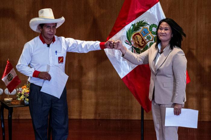Peruvian rival presidential candidates Pedro Castillo (L), of the Peru Libre party, and Keiko Fujimori, of the Fuerza Popular party, bump fists ahead of the runoff vote