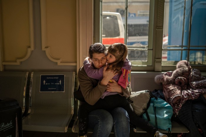 A Ukrainian evacuee hugs a child in the train station in Przemysl, near the Polish-Ukrainian border, a month after the Russian invasion