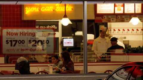 A 'Now hiring' sign is displayed on the window of a fast food restaurant in Encinitas, California