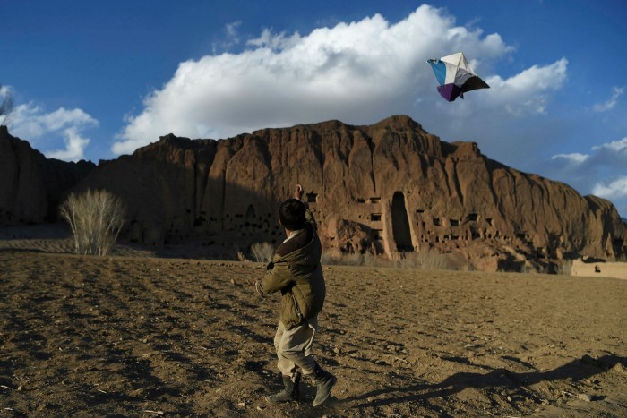 A Hazara boy flies a kite near the site of the giant Buddha statues in Bamiyan