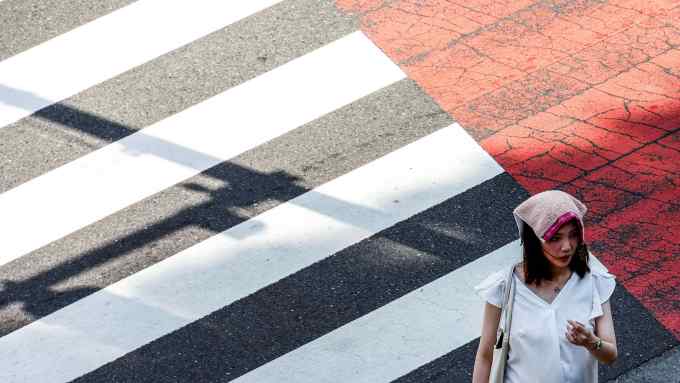 A woman crossing a street wearing a handkerchief on her head
