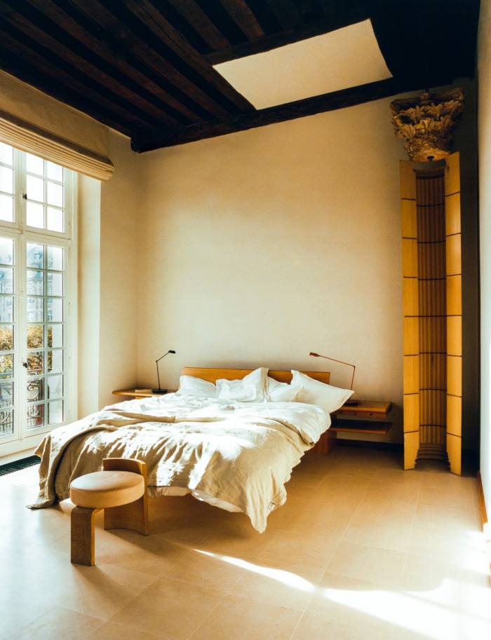 The bedroom includes a postmodern interpretation of a Greek column. A stool designed by Saraiva sits at the foot of the bed