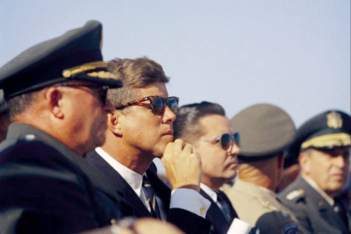 John F Kennedy sitting beside army officers