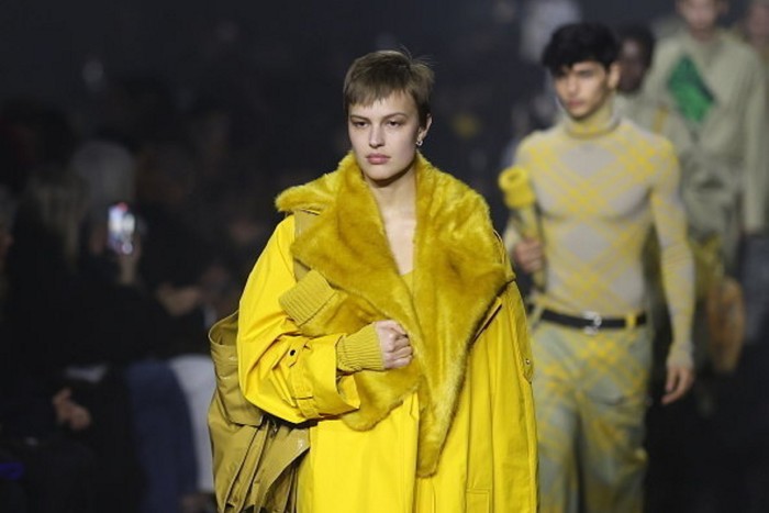 A model in a daffodil yellow coat with faux fur collar