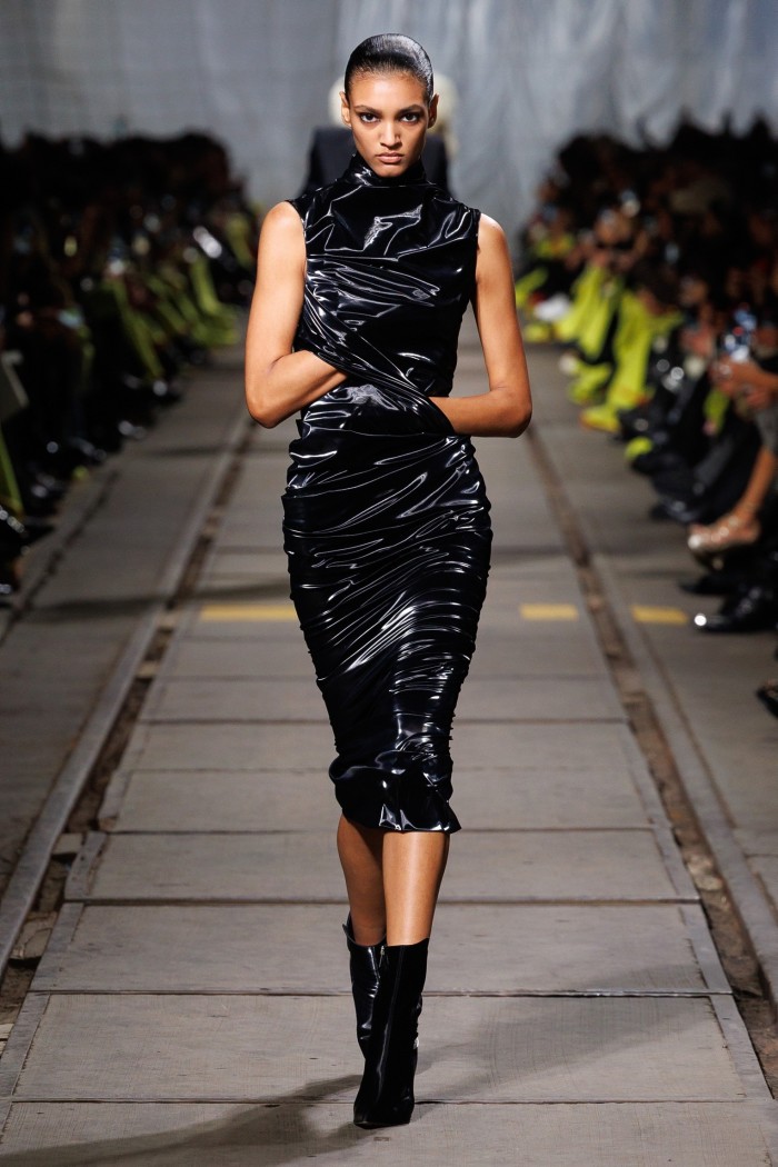 A model on the catwalk in shiny black sleeveless dress