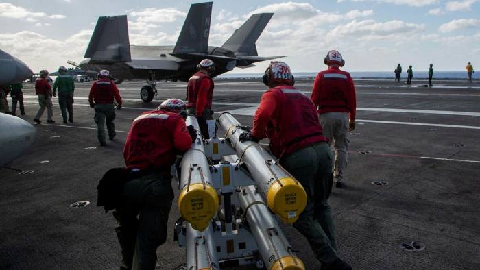US Marines loading an F-35C Lightning II with AIM-120 air-to-air missiles