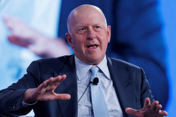 David Solomon, wearing a suit and tie, gestures while talking