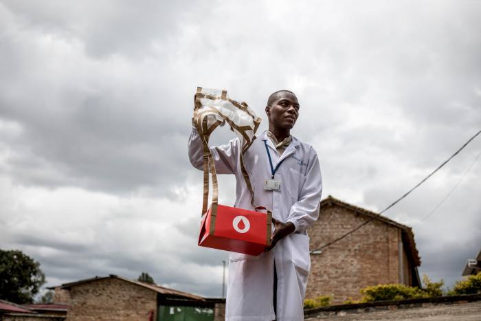 Zipline drones - Kabgayi hospital lab technician Prosper Uzabariho collects a package containing blood dropped by paper parachute from the Zipline  drone to the hospital.
