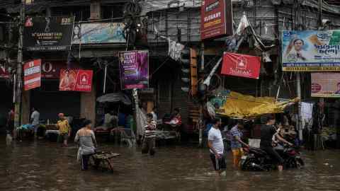 Indian residents walk along a flooded street following monsoon rain in Kolkata last month