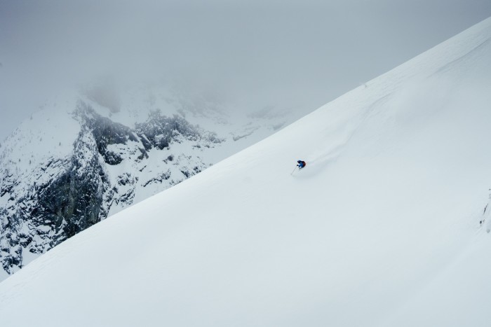 A single skier skis down a snow covered slope