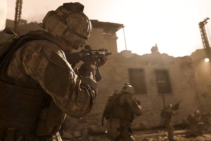 A soldier in combat uniform with a rifle approaches a building in what appears to be a Middle Eastern city.