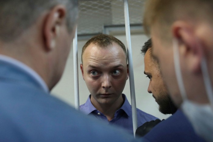 Ivan Safronov stands inside a defendants’ cage before a court hearing on suspicion of treason last year. Ivan Pavlov, a lawyer who faced charges for disclosing information from the trial, is now in Georgia