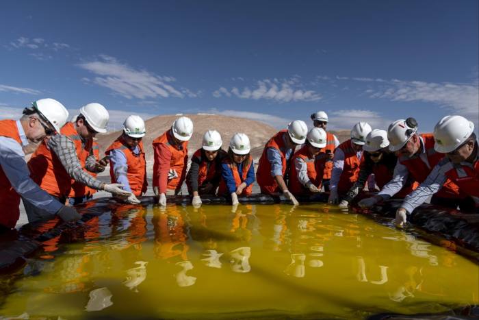 La gente inspecciona una piscina de salmuera en una mina de litio en el salar de Atacama en el desierto de Atacama, Chile