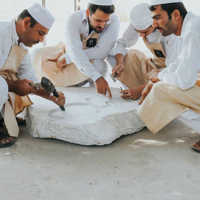 Four men sit around a slab of stone selected for sculpting