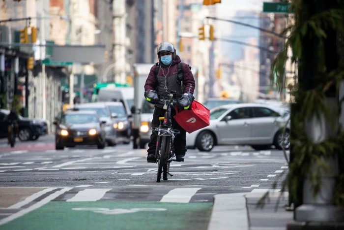 A DoorDash delivery cyclist carries a delivery through New York 