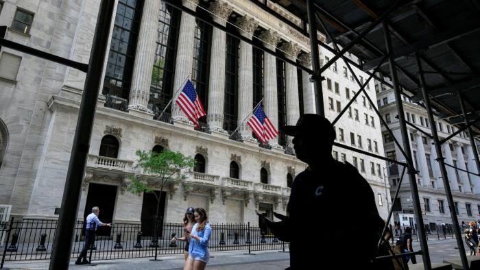 People walk past the New York Stock Exchange on Wall Street